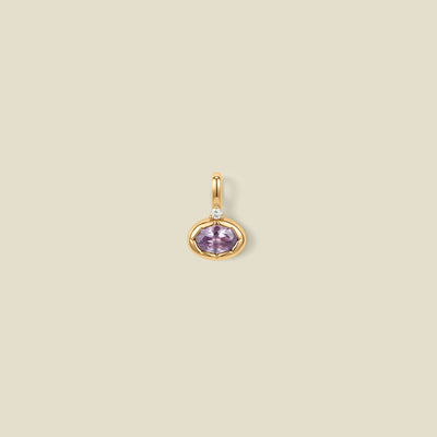 A gold oval pendant charm with a light purple bezel-set oval gemstone and a clear accent stone on top, set against a solid beige background.