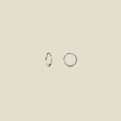 Small thin silver hoops against a neutral background.