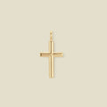 A simple polished gold cross pendant charm, set against a solid beige background.