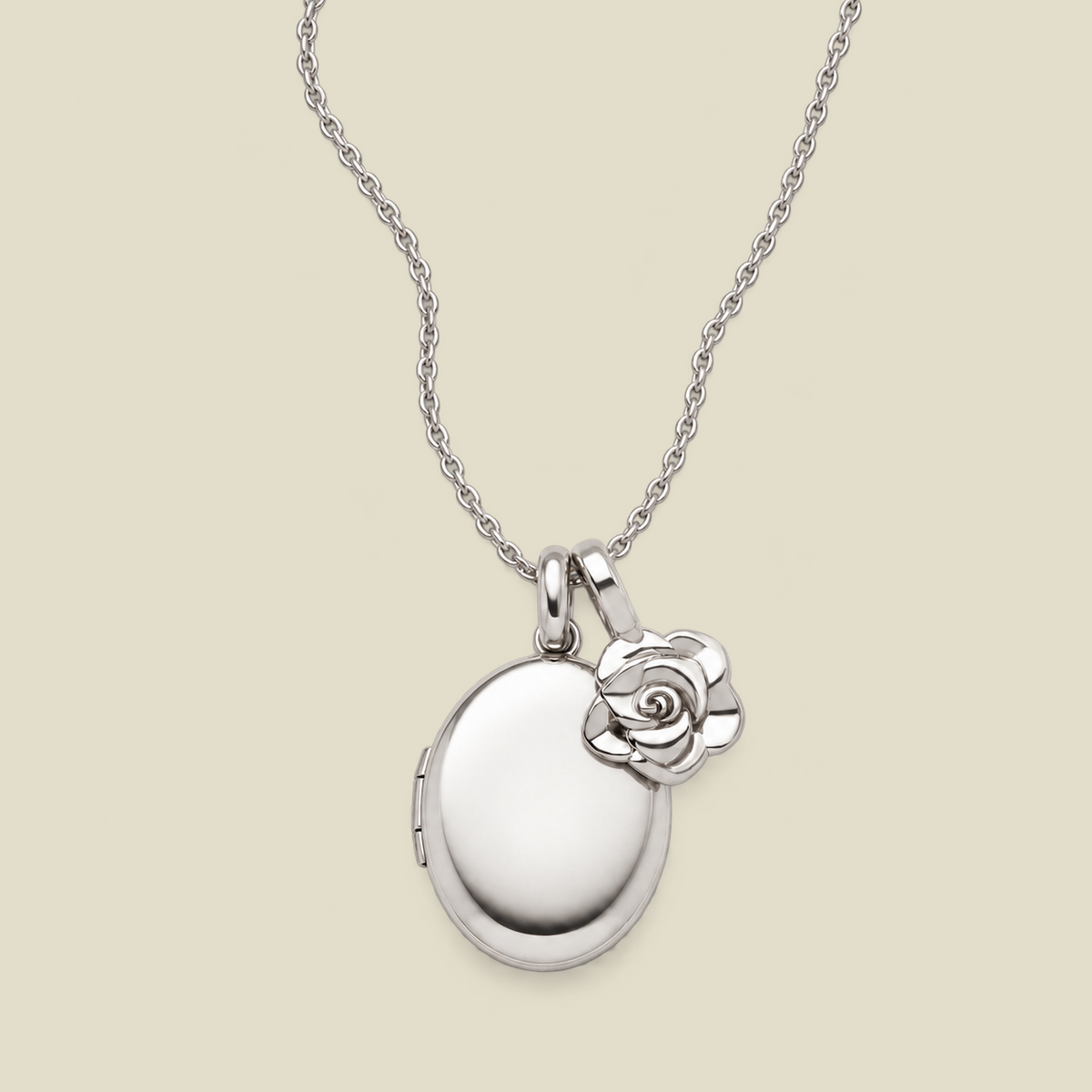 A silver locket necklace with an oval locket and a small rose charm, displayed on a light beige background.
