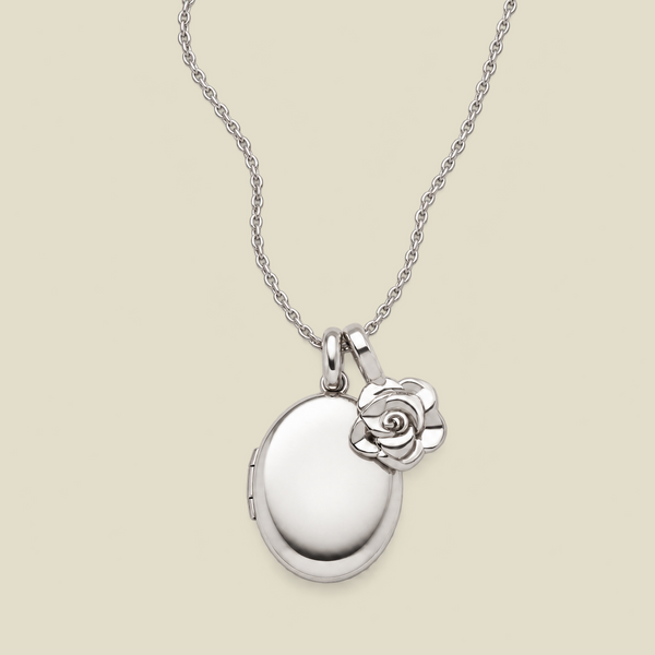 A silver locket necklace with an oval locket and a small rose charm, displayed on a light beige background.