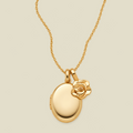 A polished gold locket necklace with an oval pendant and a small rose charm, shown on a light beige background.