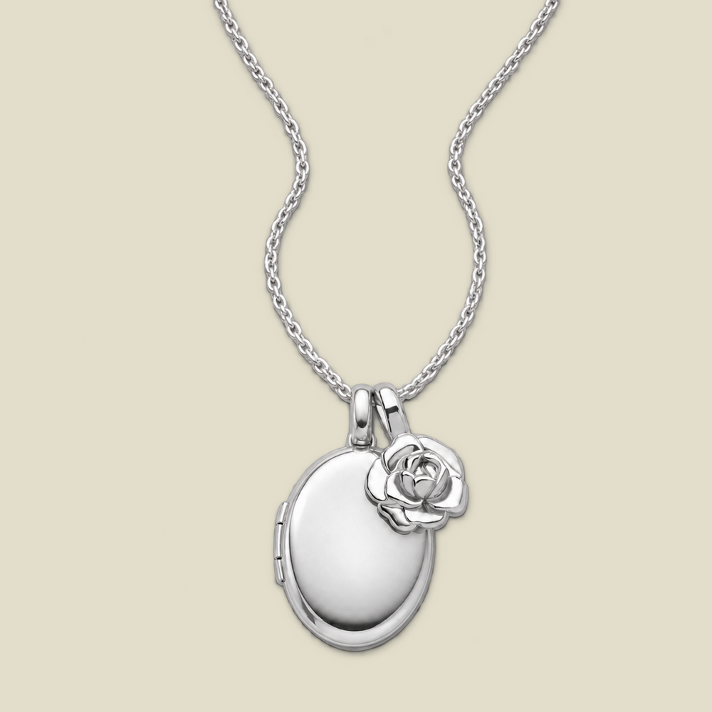 A silver locket necklace with an oval locket pendant and a small peony charm, displayed on a light beige background.