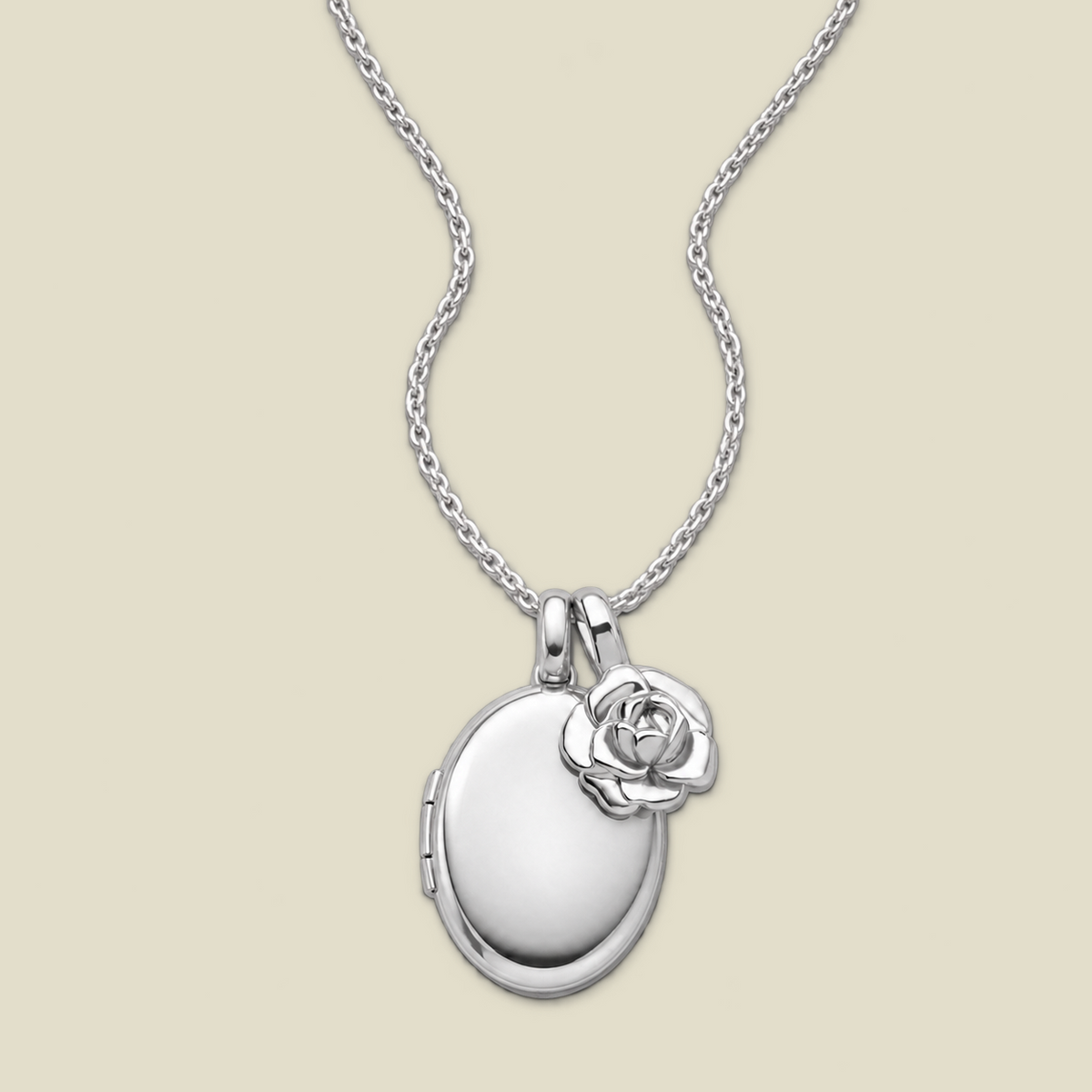 A silver locket necklace with an oval locket pendant and a small peony charm, displayed on a light beige background.