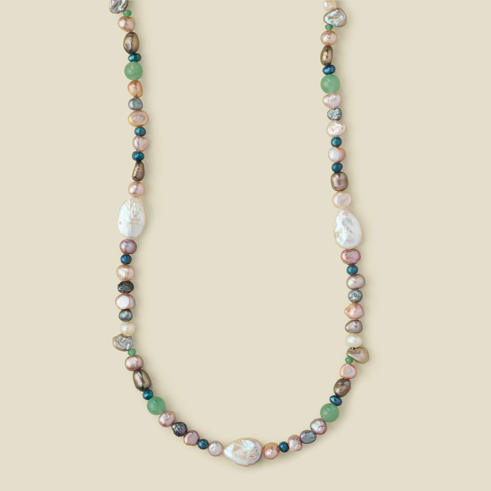 A multi-colored baroque pearl necklace with green, pink, white, and gray pearls,  displayed on a solid beige background.