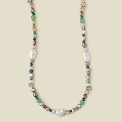 A multi-colored baroque pearl necklace with green, pink, white, and gray pearls,  displayed on a solid beige background.