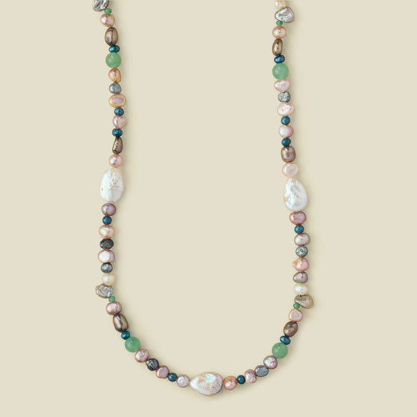 A multi-colored baroque pearl necklace with green, pink, white, and gray pearls,  displayed on a solid beige background.