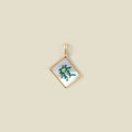 A square diamond-shaped mahjong tile pendant with a gold-tone border and a white inlay featuring a green Chinese character, shown on a solid beige background.