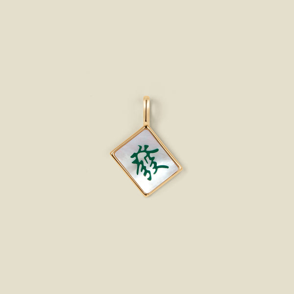A square diamond-shaped mahjong tile pendant with a gold-tone border and a white inlay featuring a green Chinese character, shown on a solid beige background.