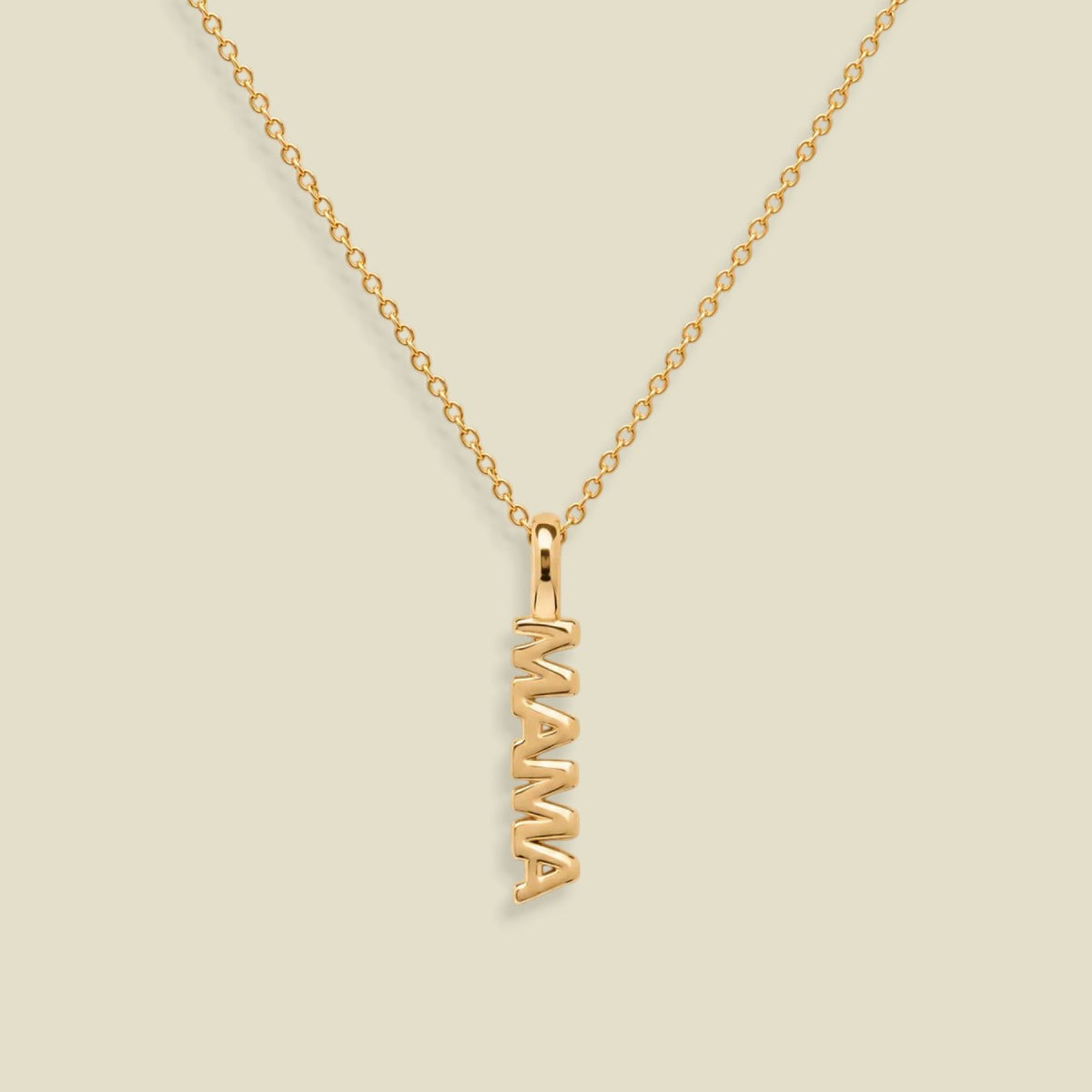 A gold chain necklace with a vertical 'MAMA' nameplate pendant, shown on a solid light beige background.