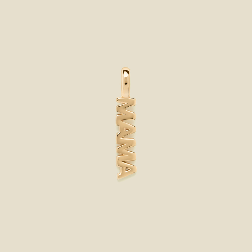 A vertical gold-tone pendant spelling 'MAMA' in an openwork font, centered on a solid light beige background.