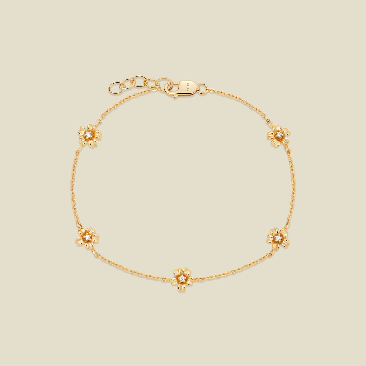 A delicate gold chain bracelet featuring five ornate, textured gold cherry blossom charms with small clear stones, arranged in a circle on a light beige background.