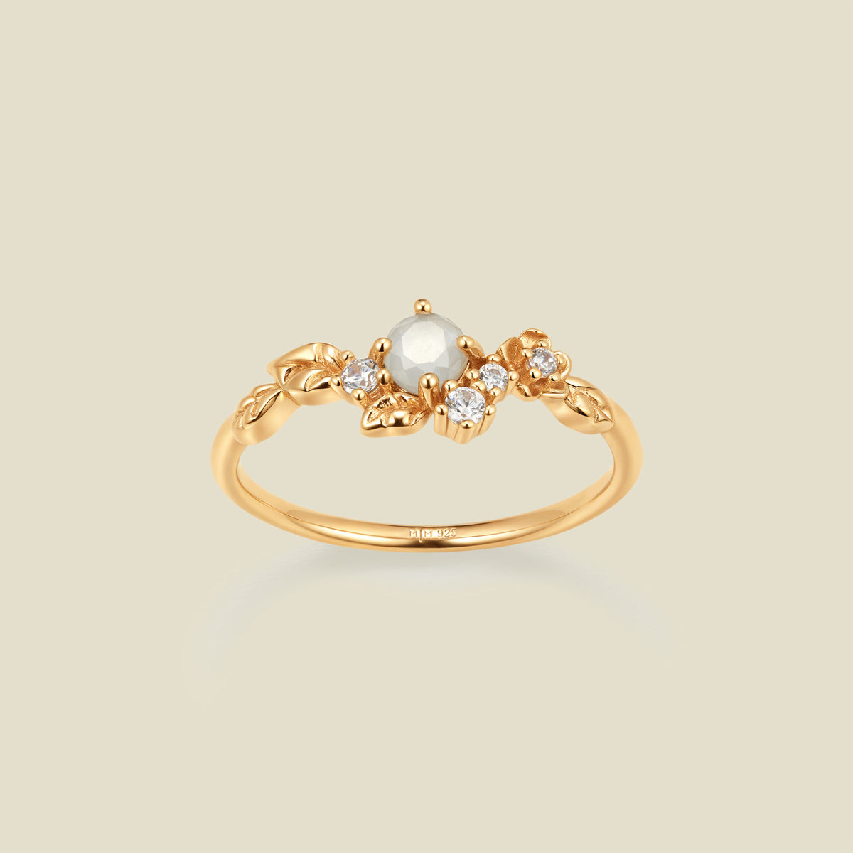 Gold ring with floral embellishments and white and clear prong-set stones against a neutral background.