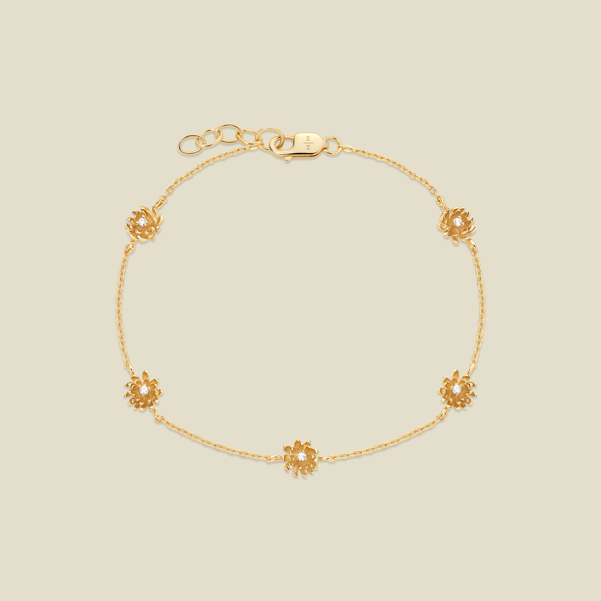 A delicate gold chain bracelet with five small chrysanthemum flower charms, each set with a clear round stone, displayed on a light beige background.