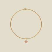 A delicate gold wire hoop necklace with a small oval-shaped pink gemstone pendant, displayed on a solid light beige background.