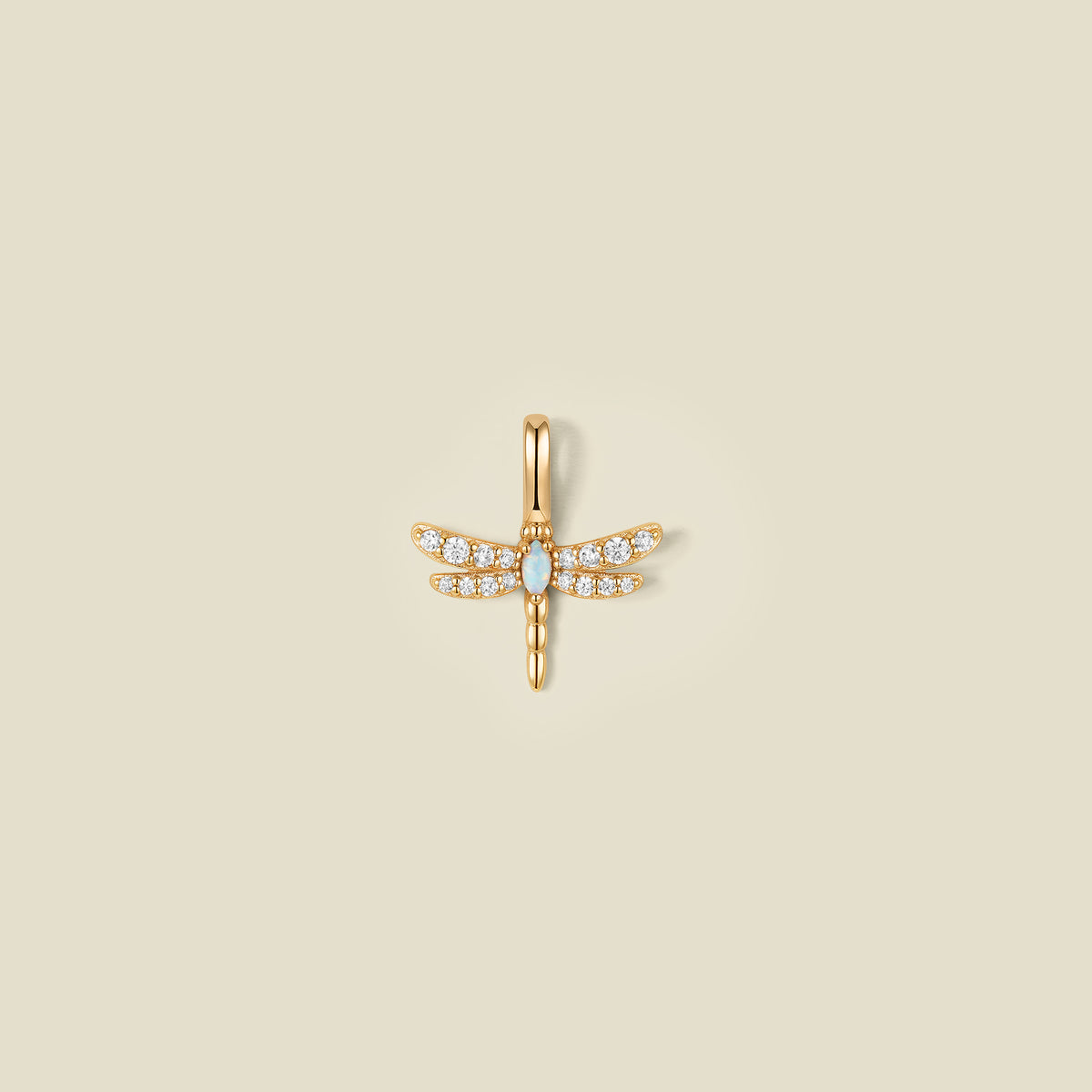 A gold dragonfly pendant charm with clear stones on the wings and an opal stone in the center.