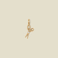 A gold scissor pendant charm with a small clear stone in the center.
