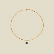 A thin gold wire hoop necklace with a small oval blue-green gemstone pendant, displayed on a solid light beige background.