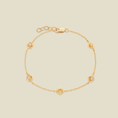 A delicate gold chain bracelet featuring five ornate, textured gold peony charms with small clear stones, arranged in a circle on a light beige background.