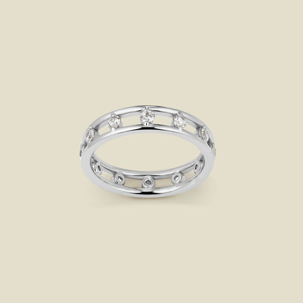 A silver eternity statement ring consisting of two thin ring bands connected by marquise-cut clear stones, shown against a solid beige background.