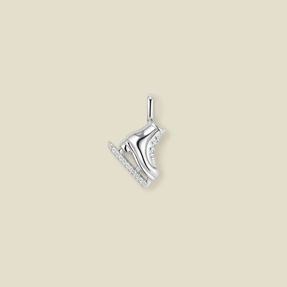 A silver ice skate charm with clear rhinestones along the blade, shown against a solid beige background.