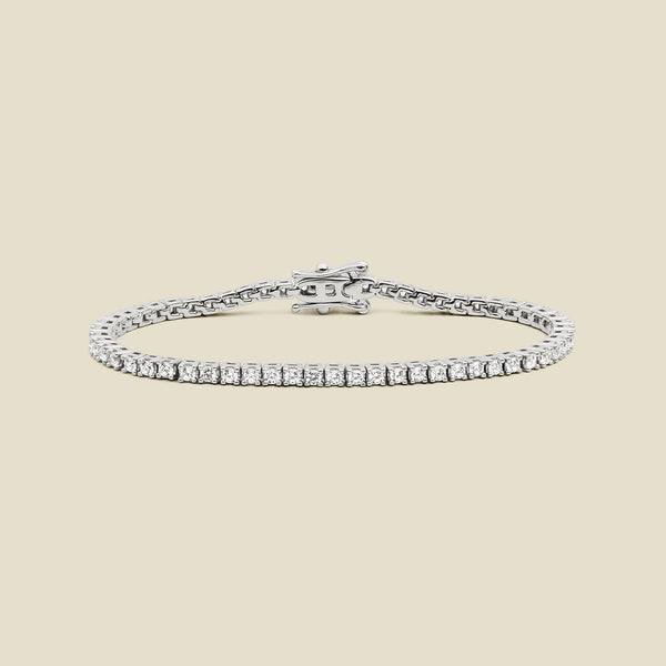 A silver tennis bracelet with clear square-cut gemstones, displayed on a solid light beige background.