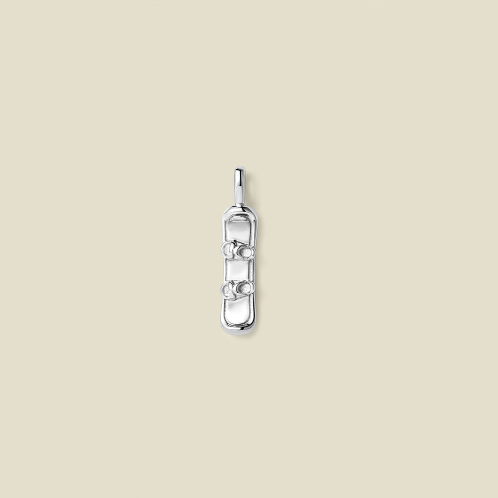 A silver pendant charm in the shape of a snowboard, set against a solid beige background.