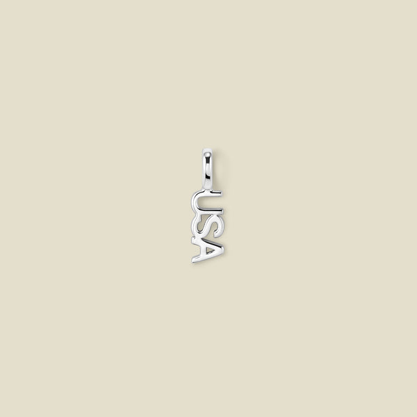 A small silver letter charm spelling 'USA' vertically, centered on a solid light beige background.