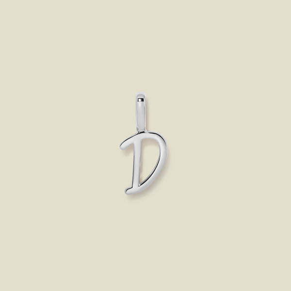 A polished silver initial pendant charm shaped like the letter 'D' in a cursive script, centered on a solid light beige background.