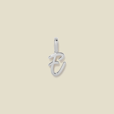 A polished silver initial pendant charm shaped like the letter 'E' in a cursive script, centered on a solid light beige background.