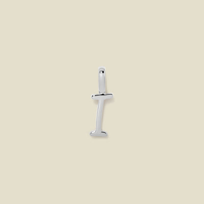 A polished silver initial pendant charm shaped like the letter 'I' in a cursive script, centered on a solid light beige background.