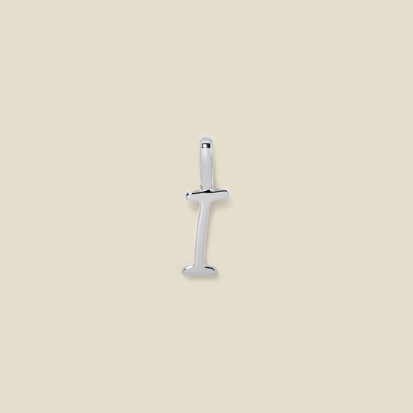 A polished silver initial pendant charm shaped like the letter 'I' in a cursive script, centered on a solid light beige background.