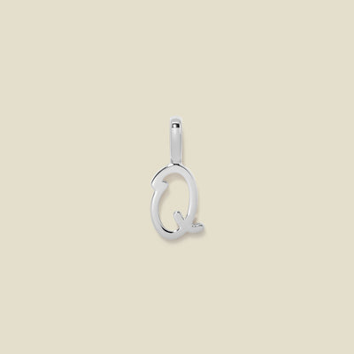 A polished silver initial pendant charm shaped like the letter 'Q' in a cursive script, centered on a solid light beige background.
