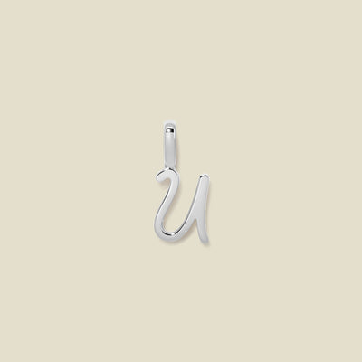 A polished silver initial pendant charm shaped like the letter 'U' in a cursive script, centered on a solid light beige background.