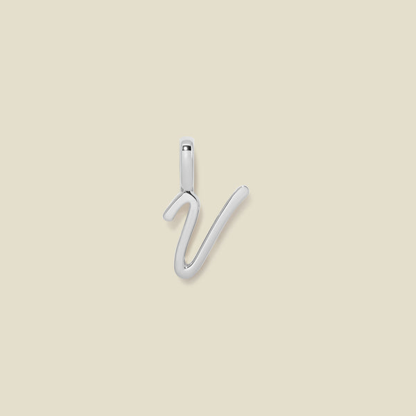 A polished silver initial pendant charm shaped like the letter 'V' in a cursive script, centered on a solid light beige background.