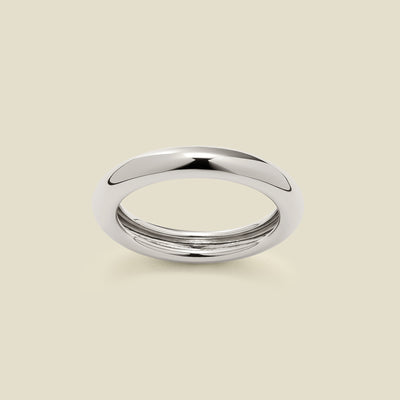 A polished, wide silver ring with a rounded domed exterior, set against a solid beige background.