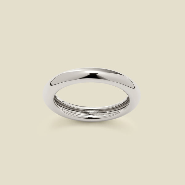 A polished, wide silver ring with a rounded domed exterior, set against a solid beige background.