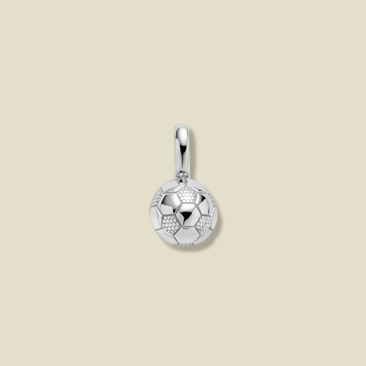 Silver pendant shaped like a soccer ball on a beige background