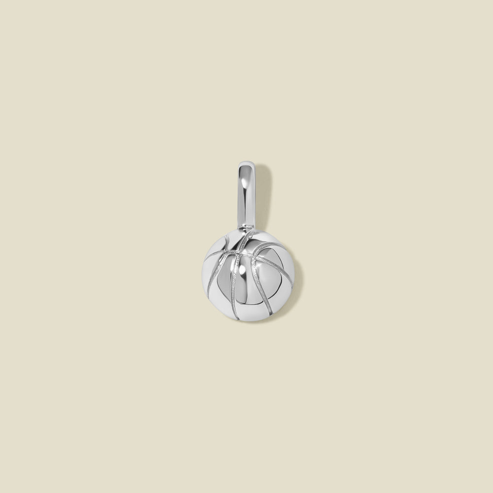 A silver basketball charm with seam details, set against a solid beige background.