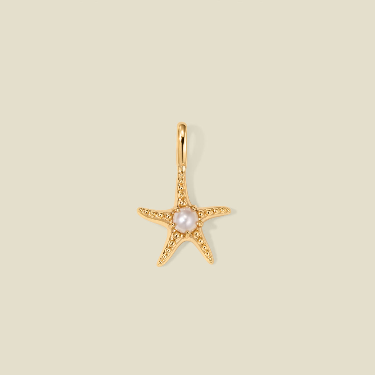 Gold starfish pendant charm with a pearl in the center on a beige background