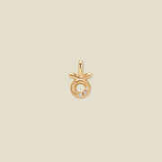 A gold pendant shaped like the Taurus zodiac symbol, featuring three small clear gemstones, centered on a solid light beige background.