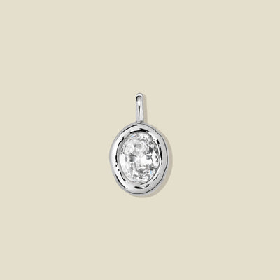 A silver bezel-set pendant charm with a large clear gemstone.