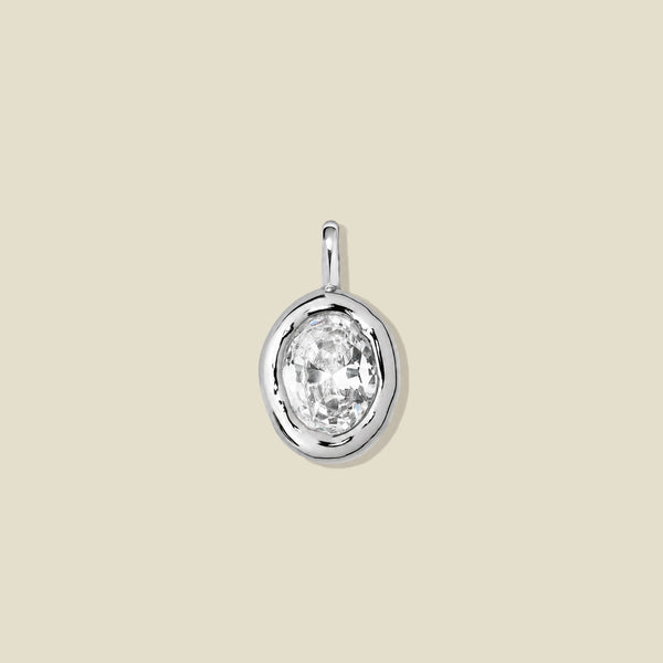 A silver bezel-set pendant charm with a large clear gemstone.