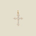 A gold cross pendant charm with clear stones across the front.