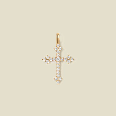 A gold cross pendant charm with clear stones across the front.