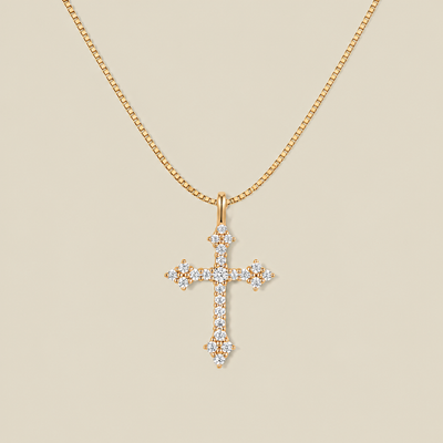 Gold cross pendant necklace with clear stones over the face on a beige background.