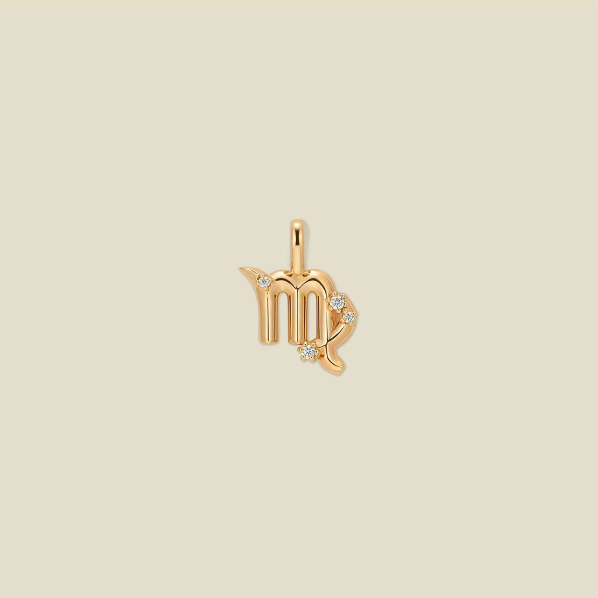 A gold pendant shaped like the Virgo zodiac symbol, featuring three small clear gemstones, centered on a solid light beige background.