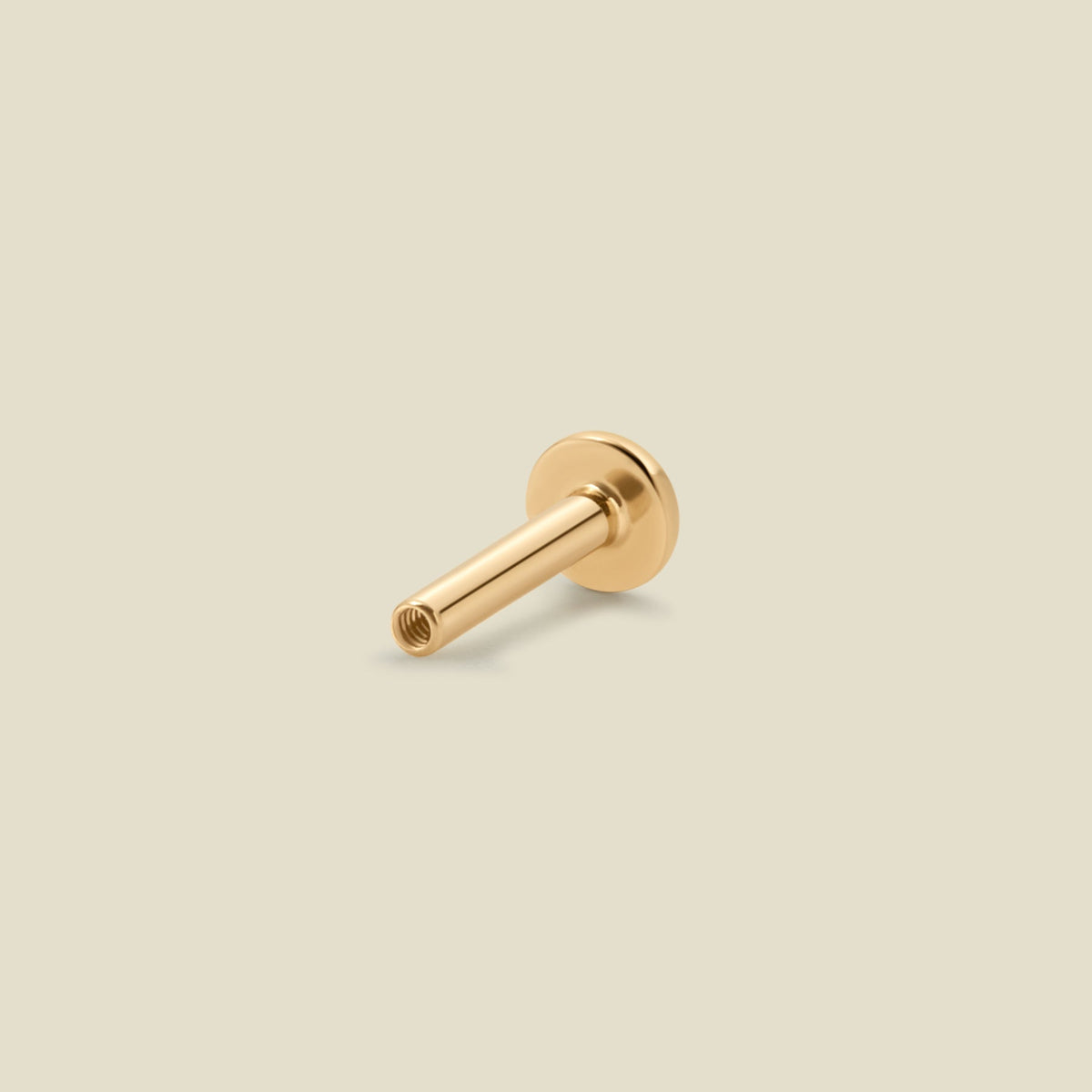 A 14k solid gold flat earring back, shown up close on a light beige background.