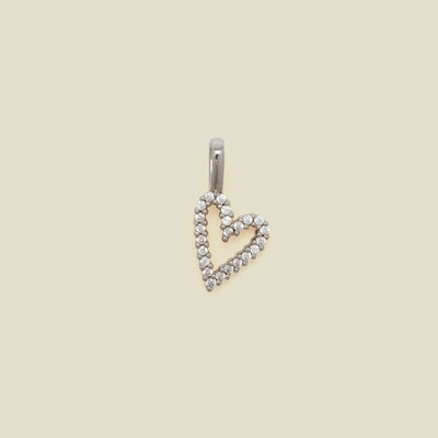 A silver heart-shaped pendant charm paved with small clear stones, shown against a solid beige background.