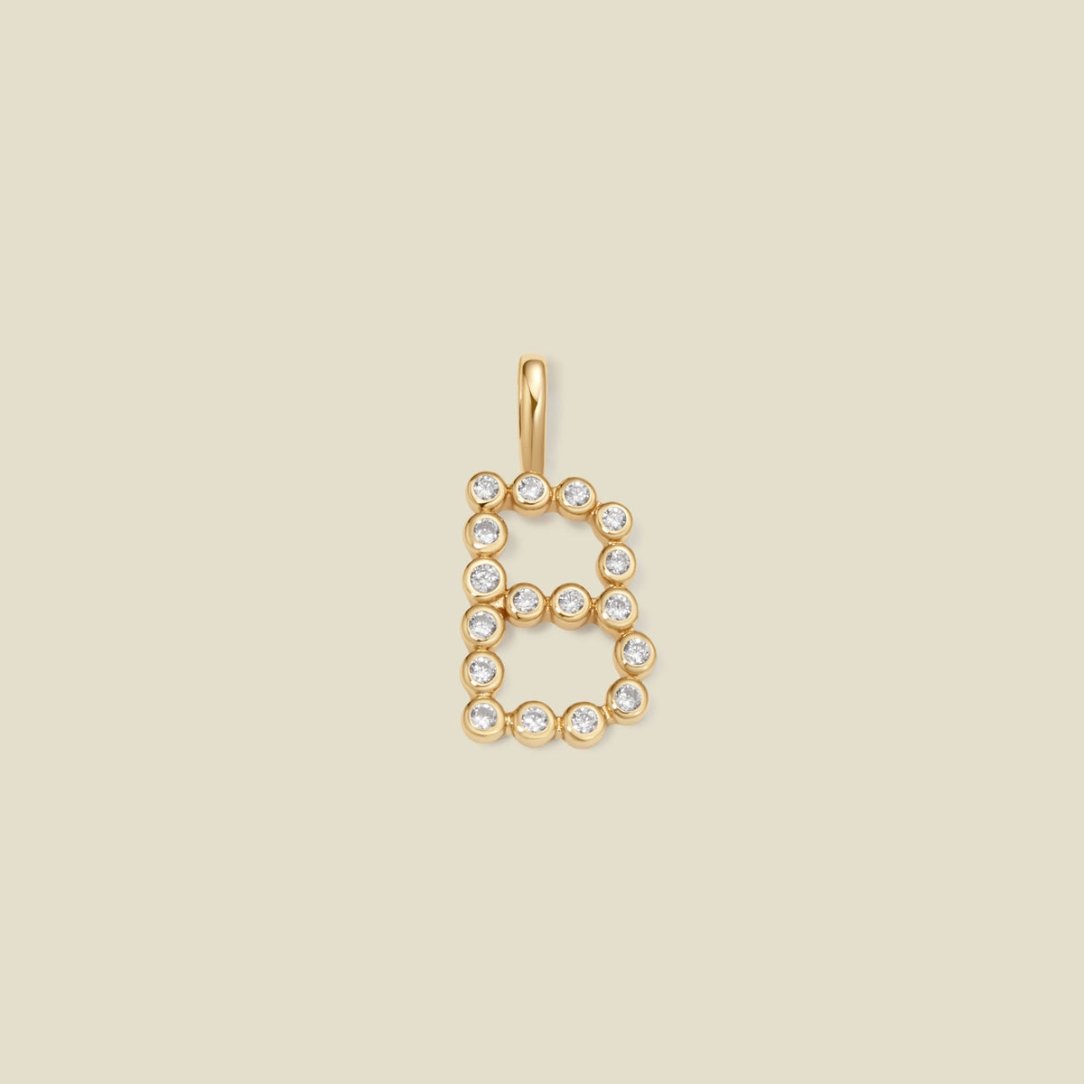 A gold letter 'B' pendant charm embellished with clear round gemstones, centered on a solid light beige background.